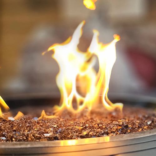 Round gas fire pit burning over fire glass media