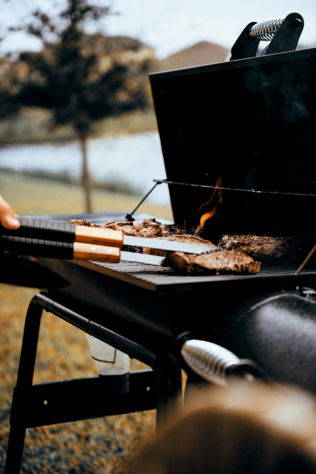 Outdoor gas grill searing steaks with lid open