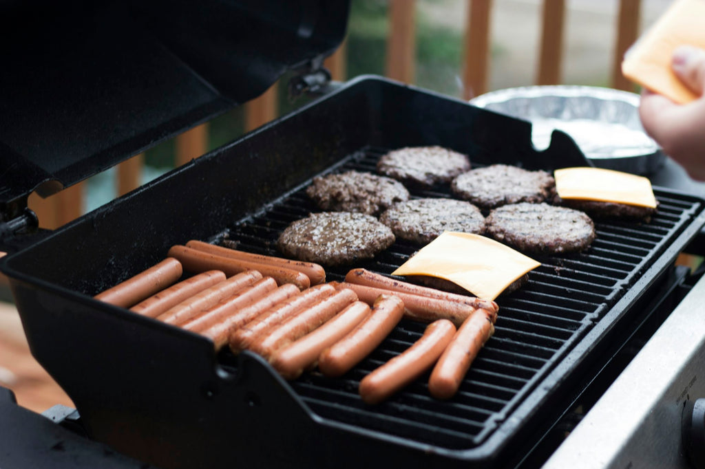 Gas grill cooking burgers and sausages