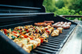 Stainless gas grill cooking skewers and sausages outdoors