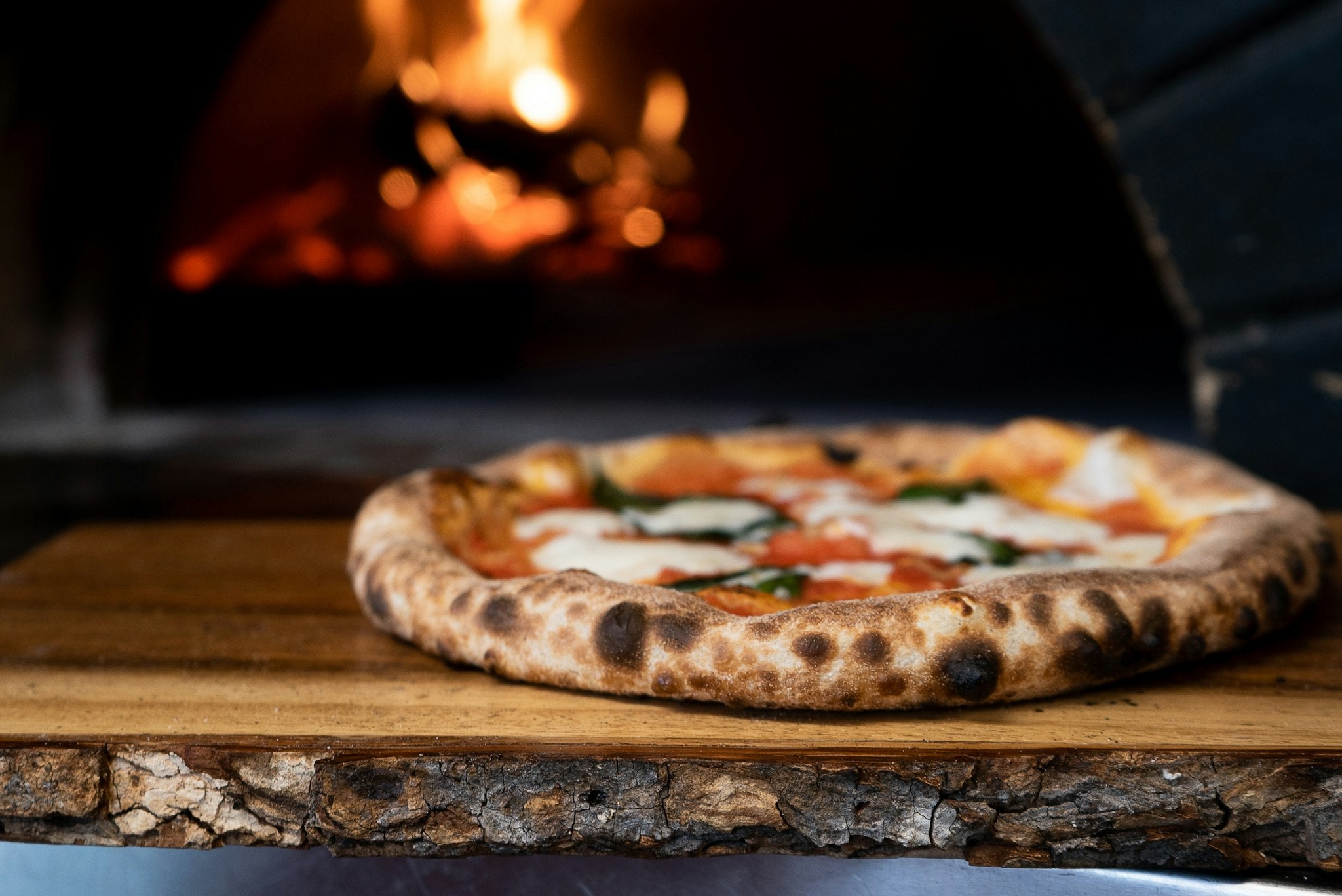 Margherita pizza fresh from the wood-fired oven on a rustic board