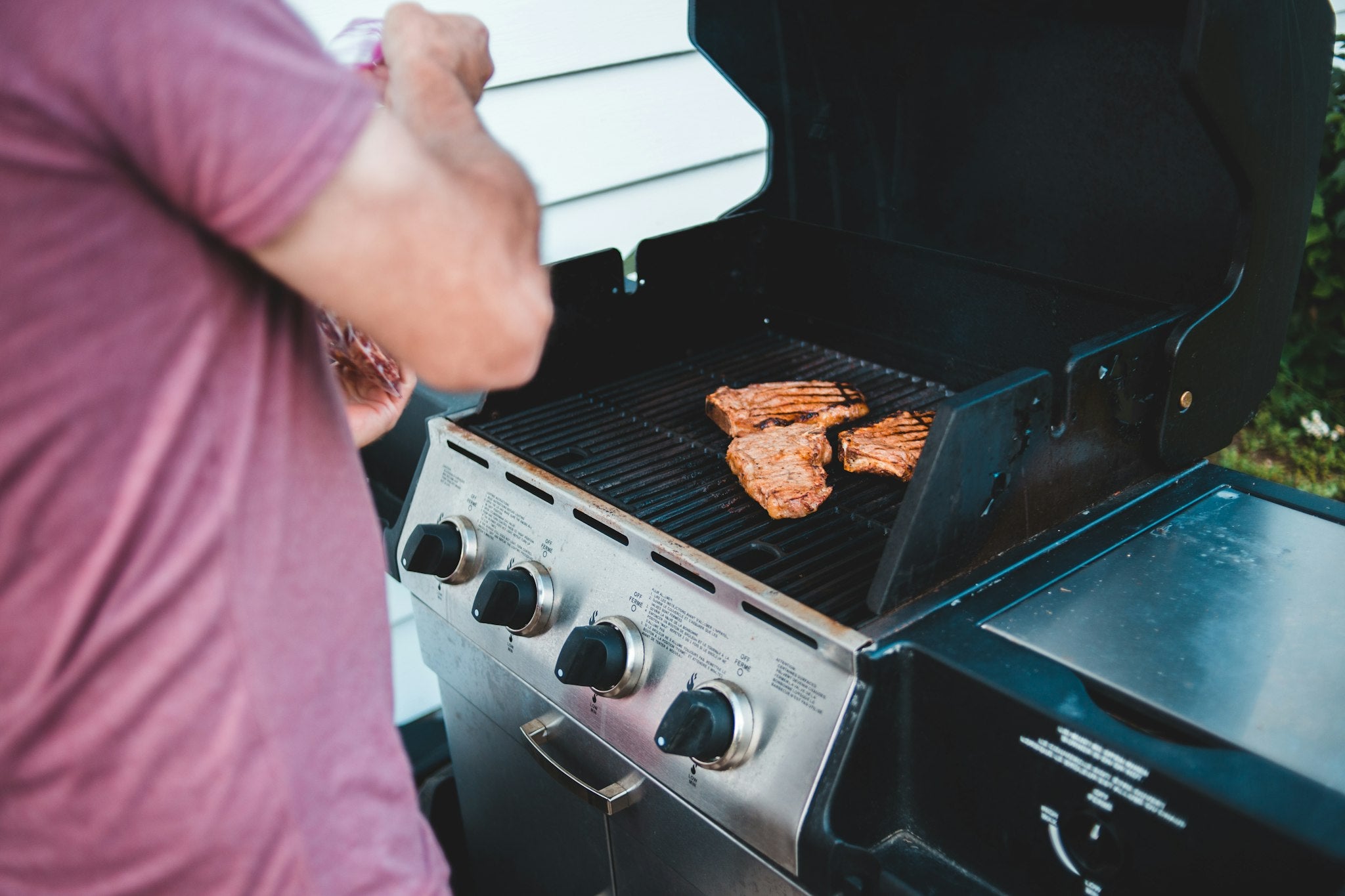 Cooking meat on a stainless steel gas grill outdoors