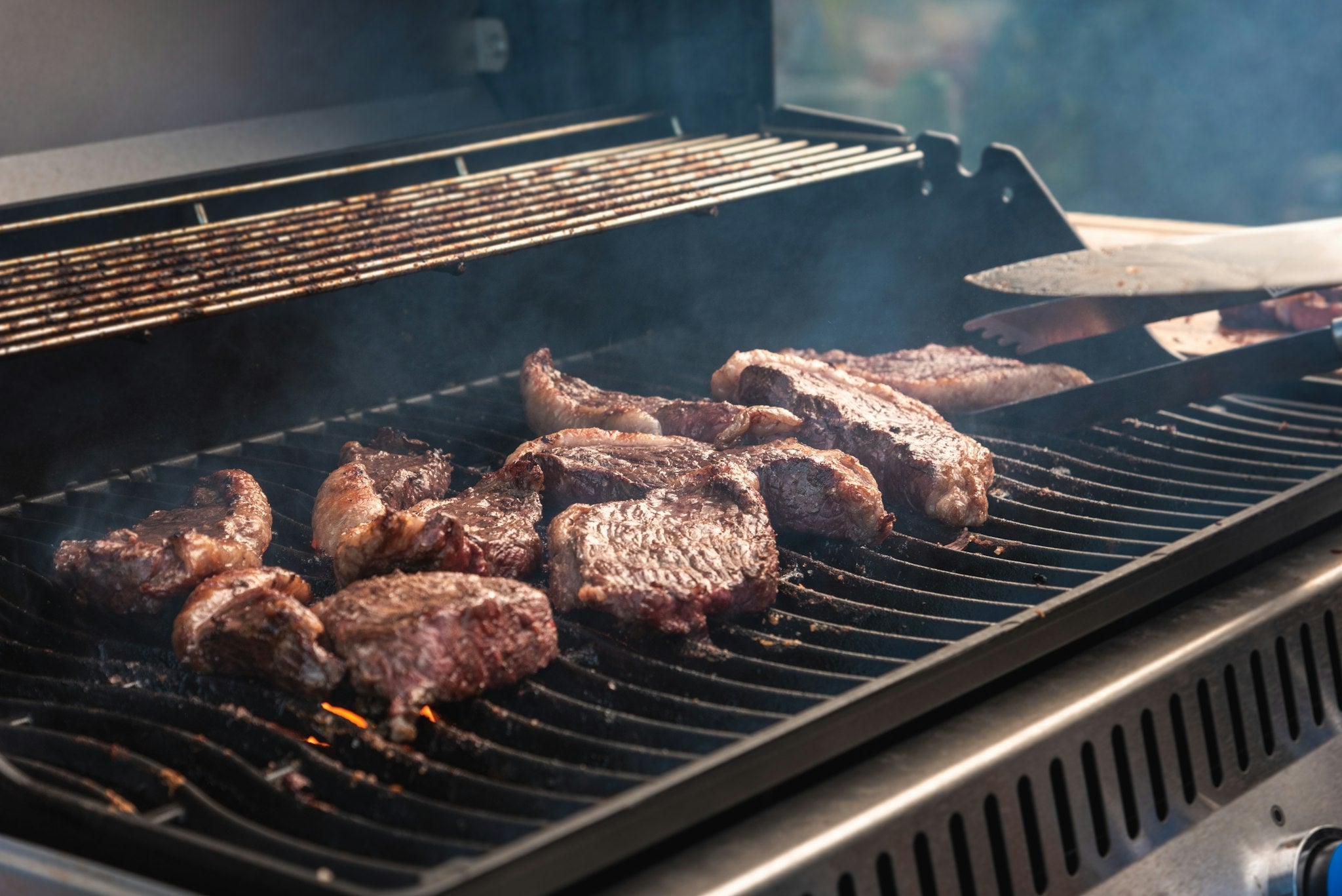 Steaks searing on gas grill grates, close-up