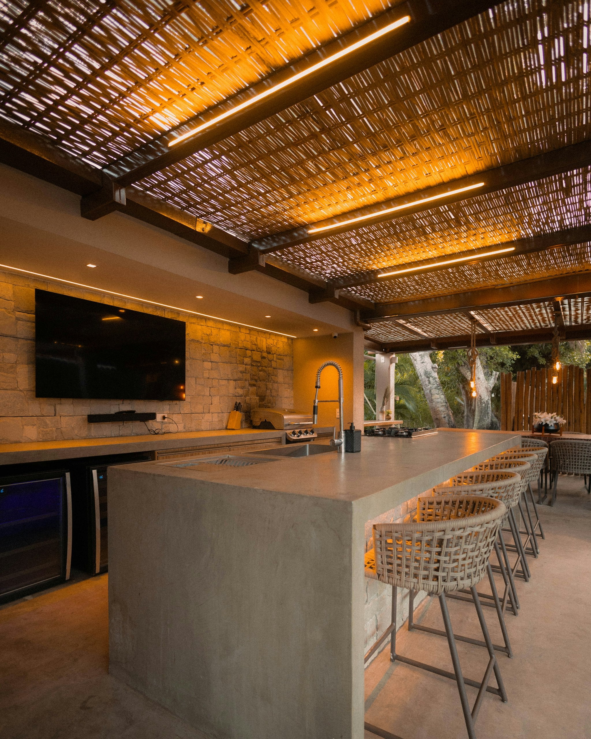 Built-in grill in a modern covered outdoor kitchen with bar seating