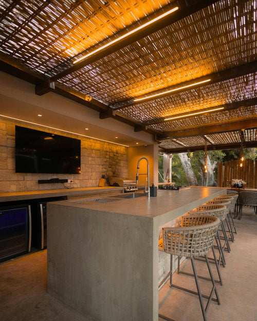 Built-in grill in a modern covered outdoor kitchen with bar seating