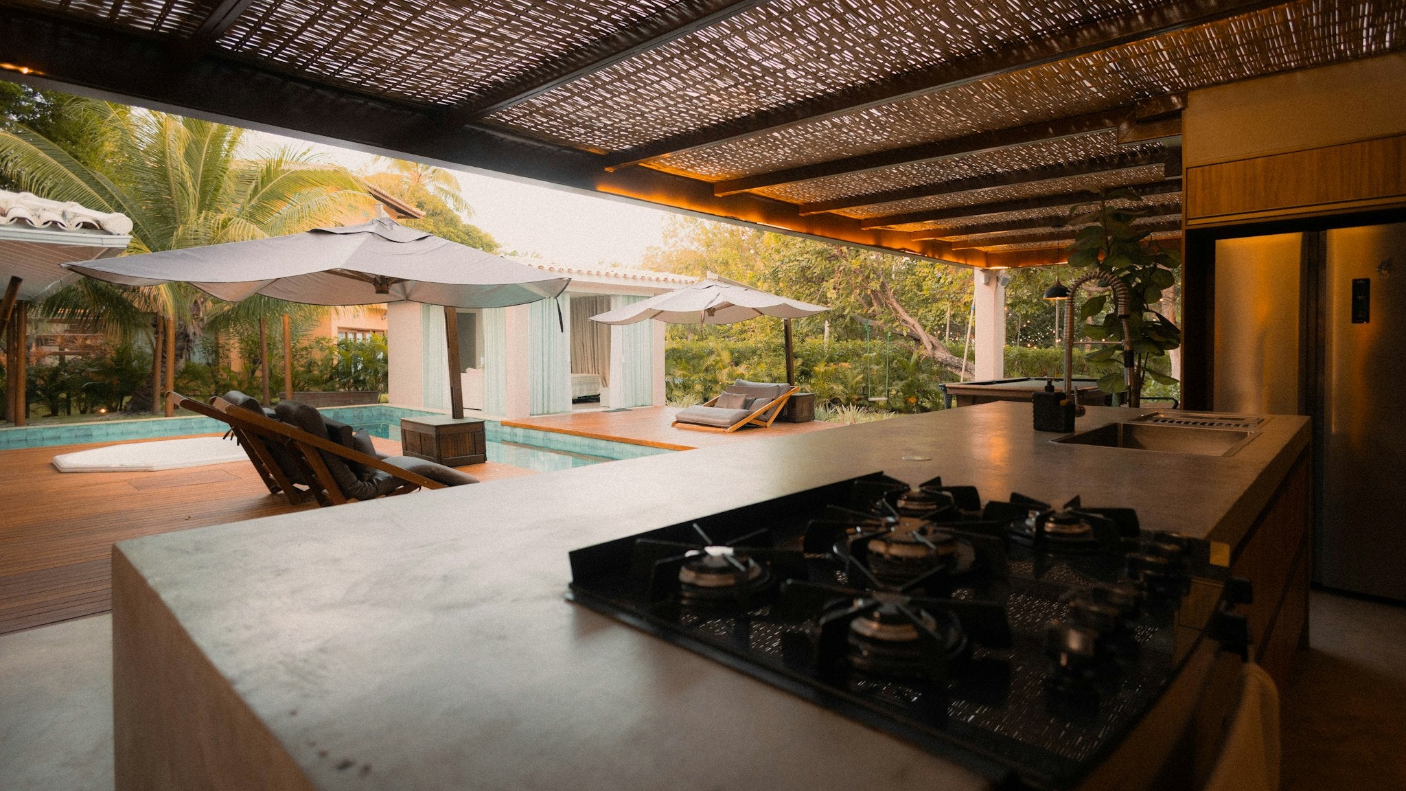 Outdoor kitchen with built-in burners overlooking a pool