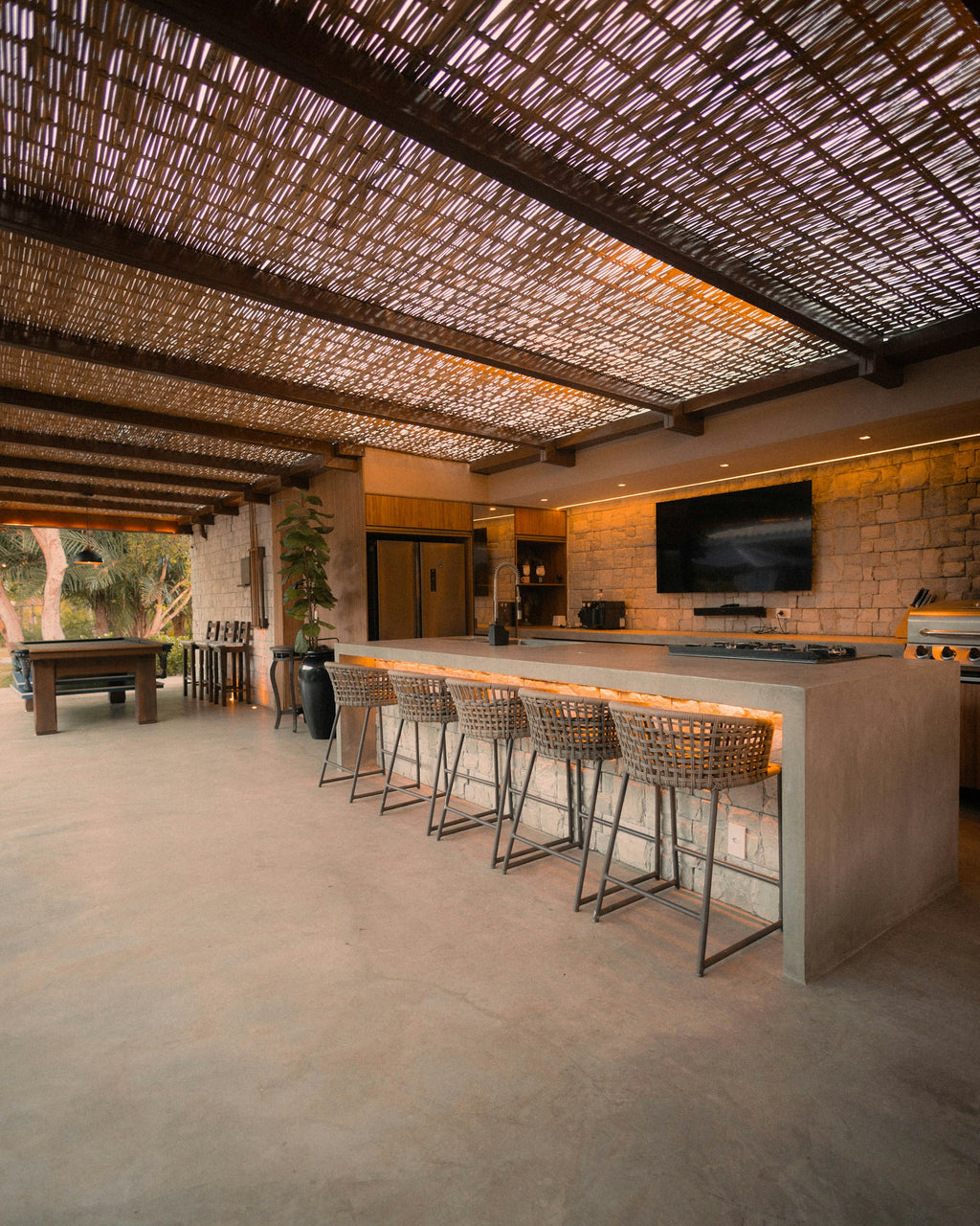 Outdoor kitchen island with bar stools and built-in cooking station